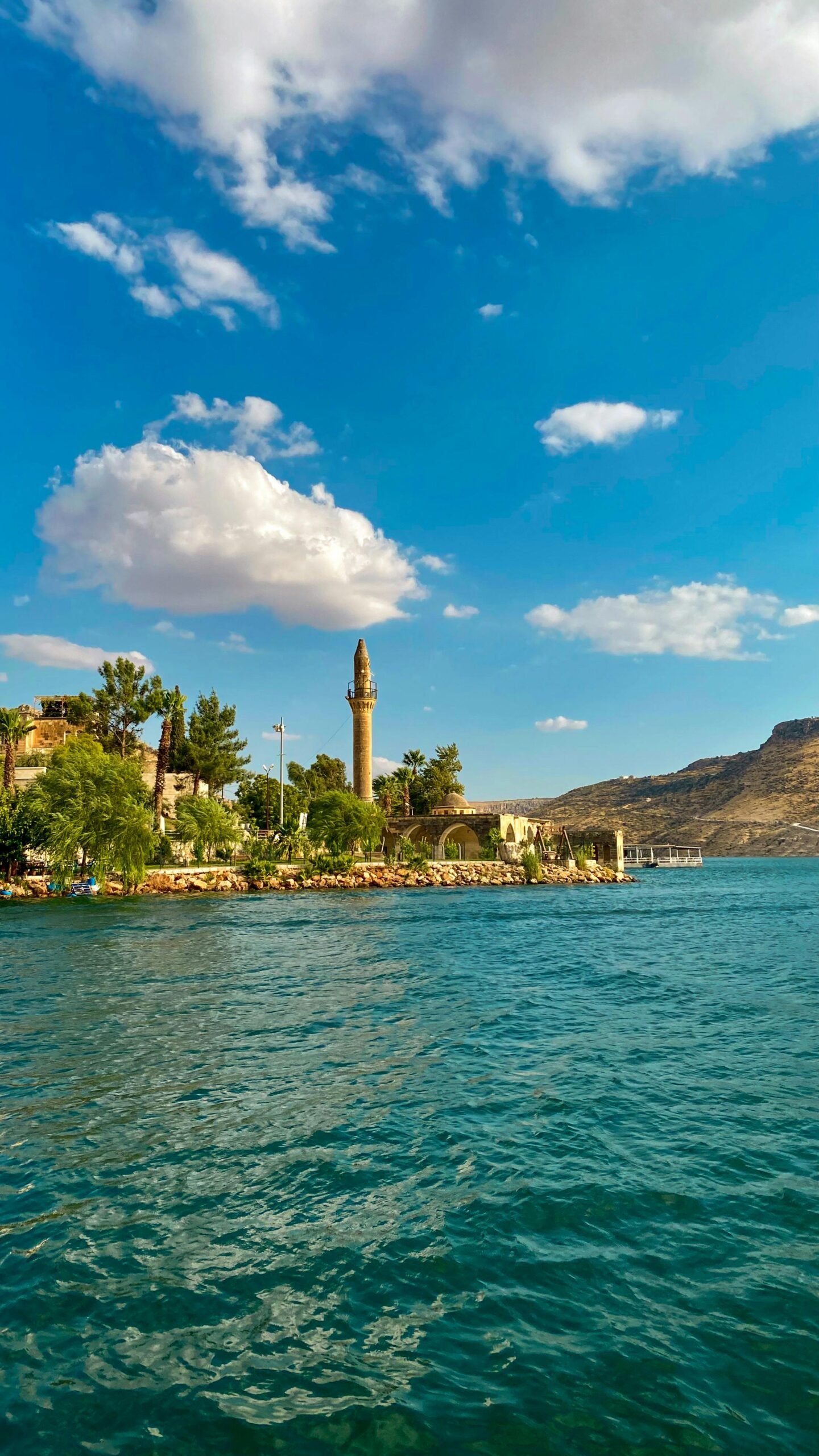 Picturesque river scene in Halfeti, Turkey with a minaret and clear blue skies.