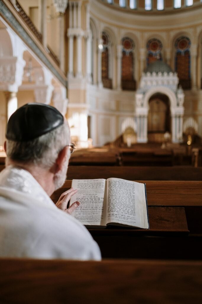 pexels-photo-5974258-5974258 A man wearing a kippah reads religious texts inside a beautifully ornate synagogue.